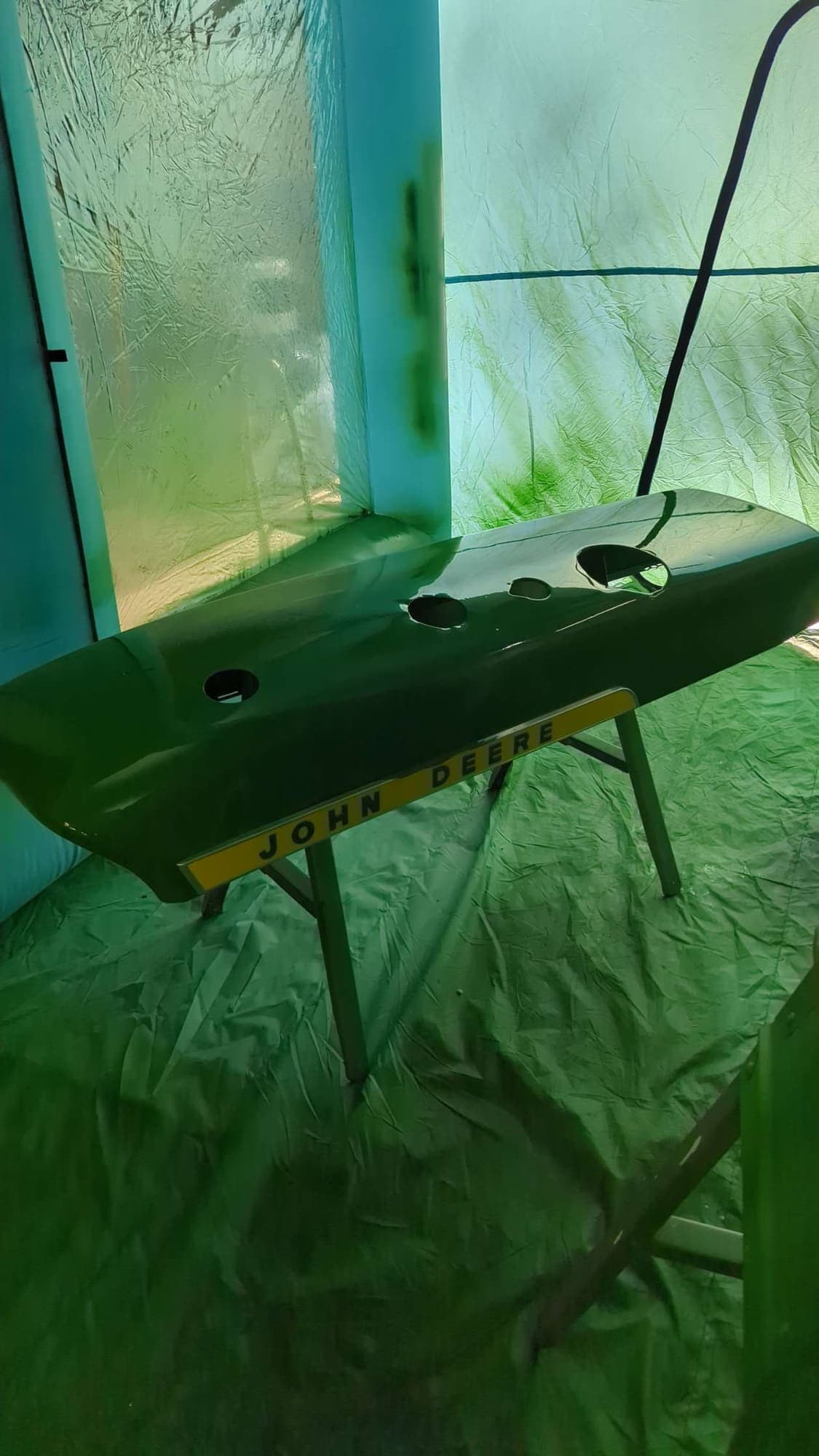 Freshly painted John Deere hood drying in the spray booth